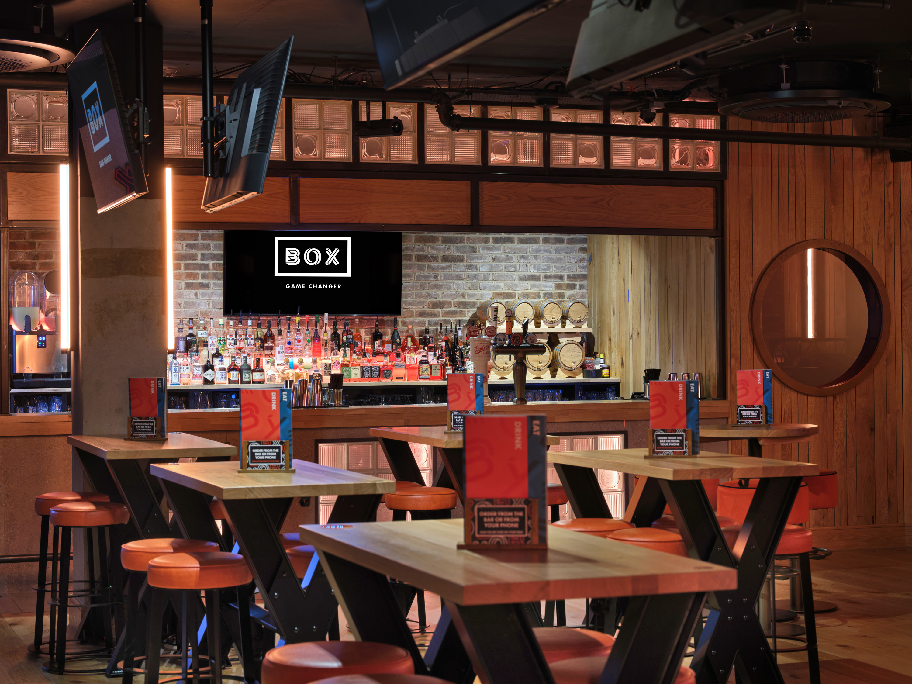 Trendy BOX Below venue with wooden tables and orange stools for casual gatherings.