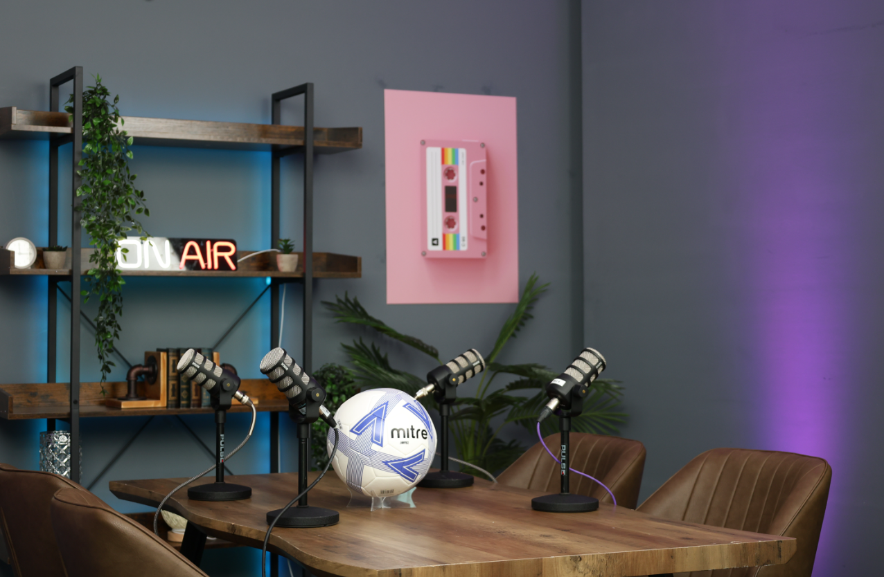 Modern podcast studio with wooden table, microphones, ideal for panel discussions.