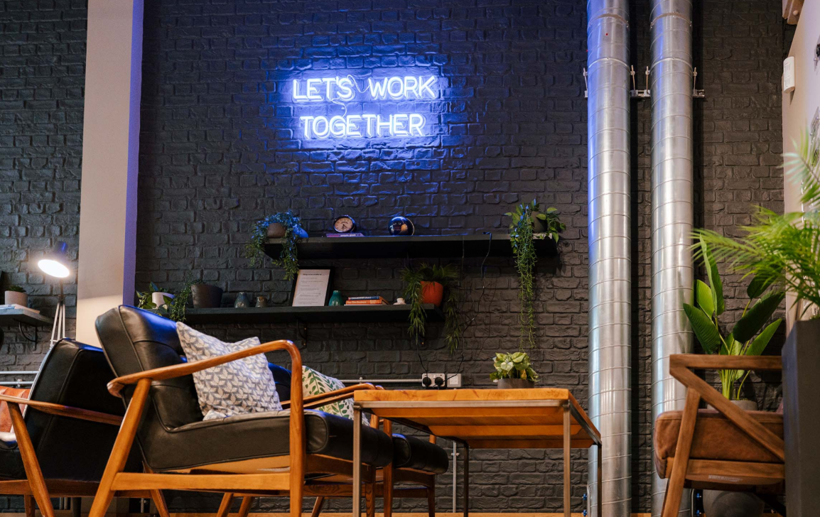 Modern collaborative workspace with neon sign, ideal for team-building and workshops.
