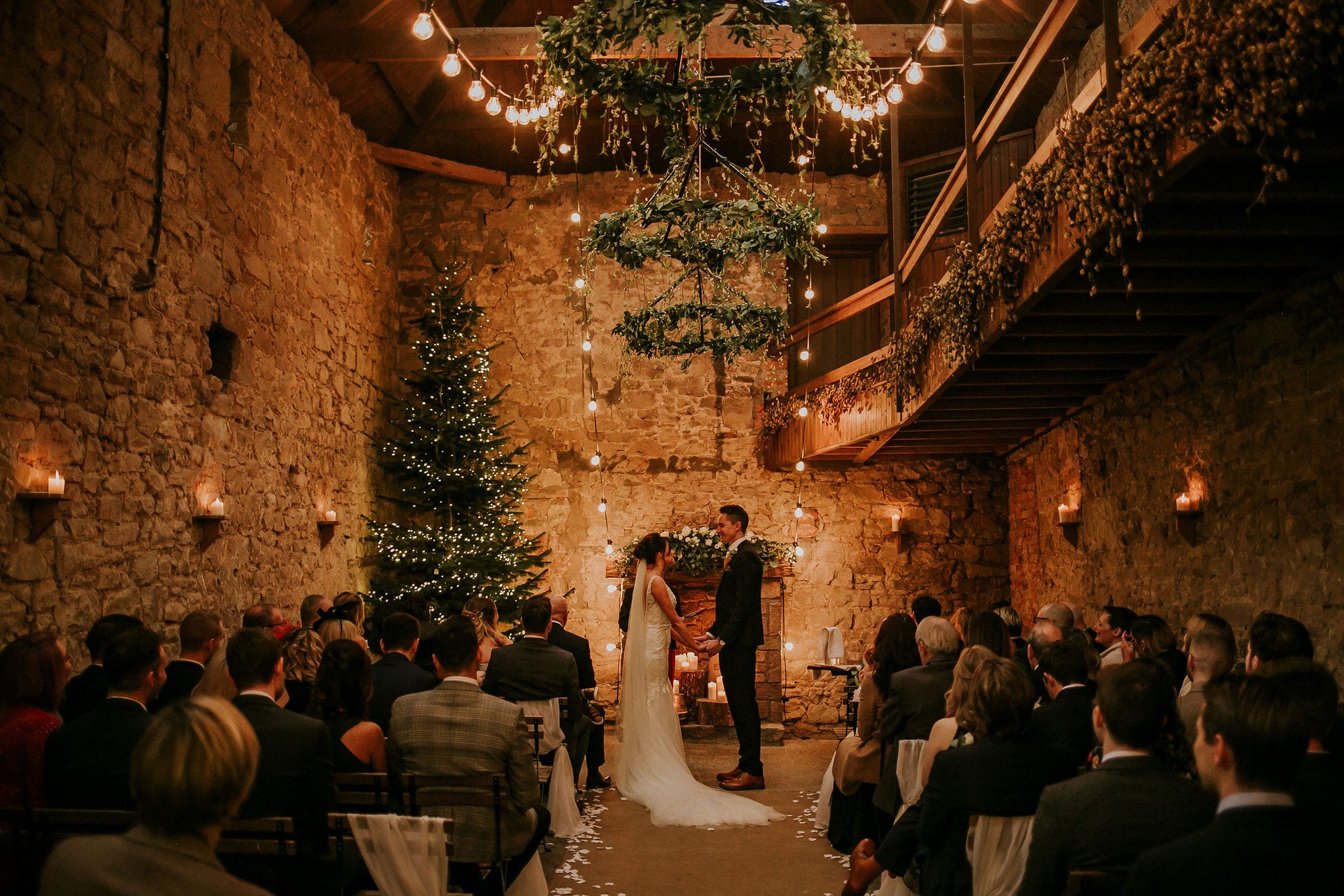Rustic Chipchase Castle Great Hall, indoor wedding ceremony with greenery and stone masonry.