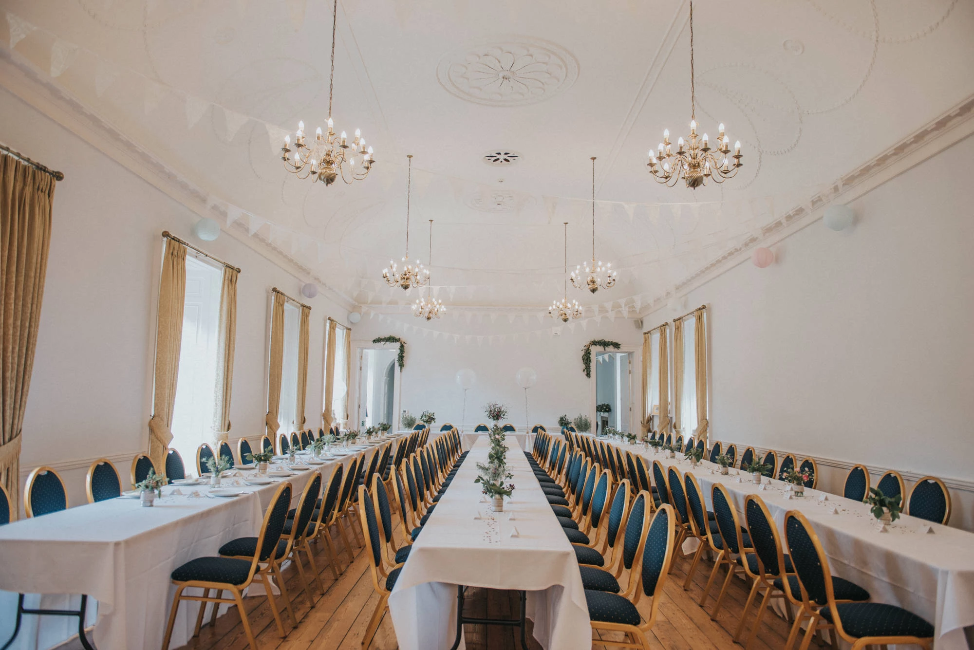 Great Hall in Hexham Abbey set for a formal event with elegant tables and chandeliers.