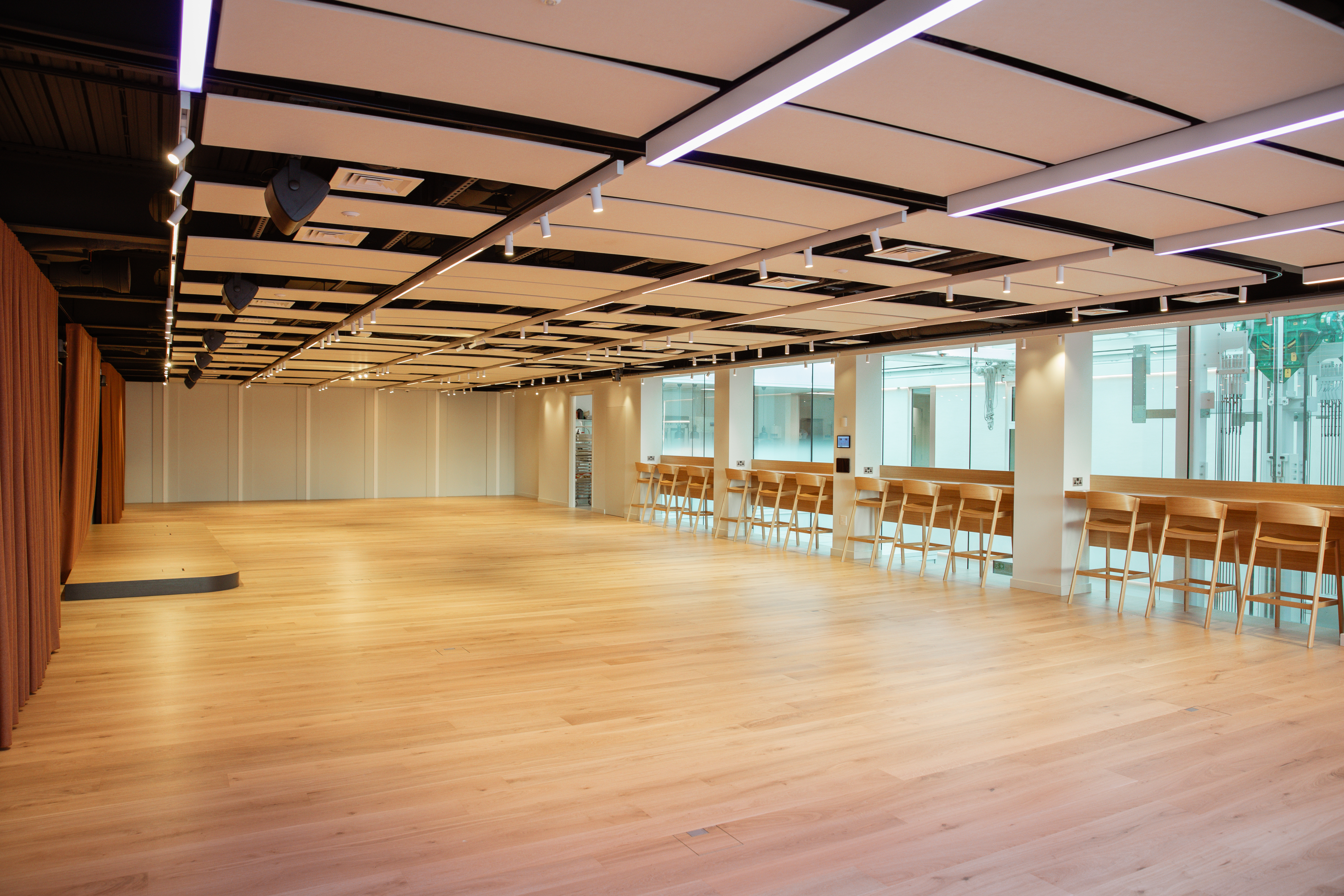 Spacious modern event venue with wooden flooring for meetings and workshops, promoting collaboration.