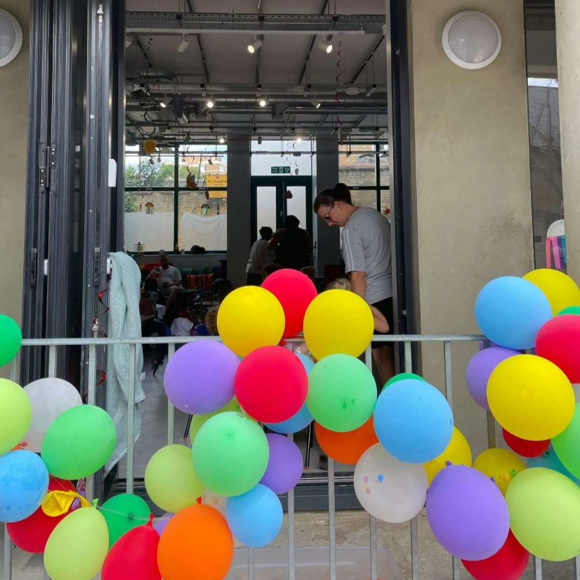Allie Harper at Ivy Street Family Centre entrance with colorful balloons for a festive event.