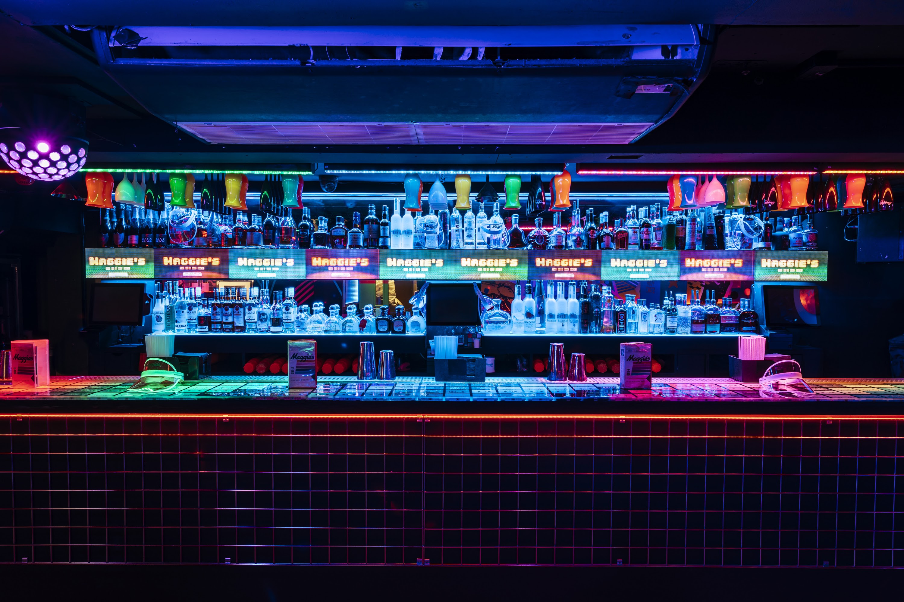 Vibrant bar setup for social gatherings with colorful lighting at Maggie's venue.