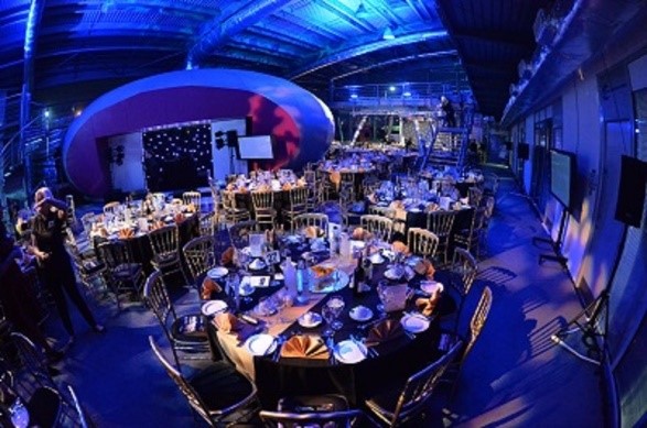 Elegant event space with fine dining setup and blue lighting for corporate events.