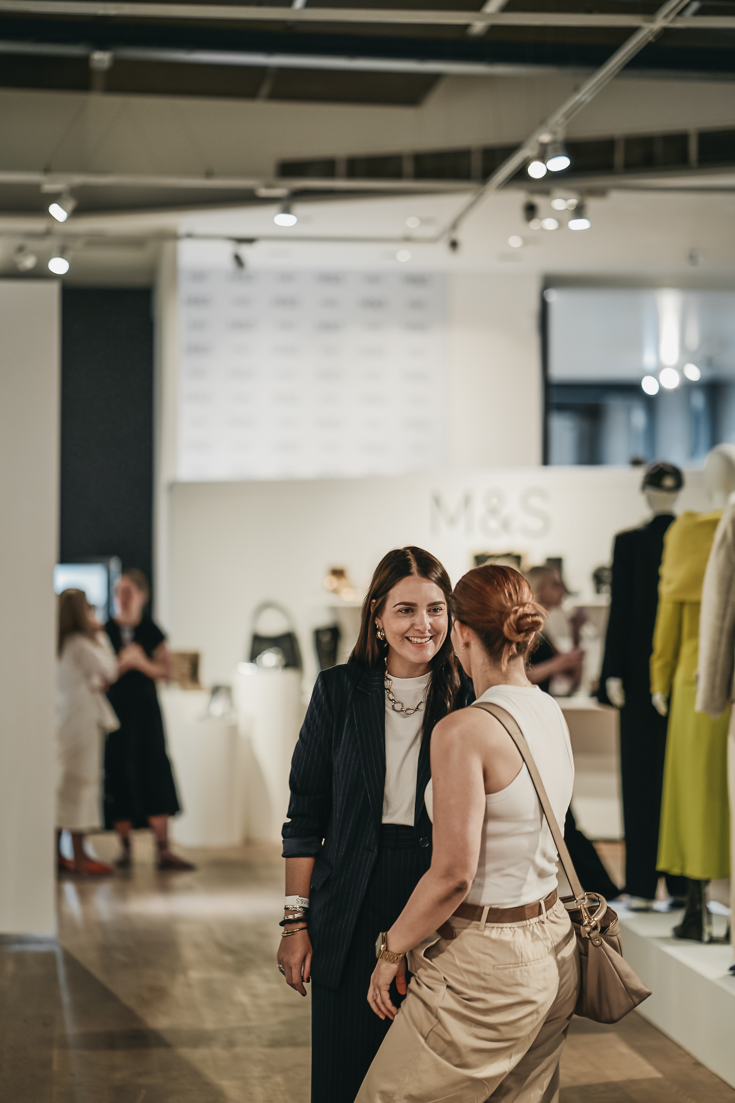 Vibrant networking event with elegantly dressed attendees at a product launch in a mall gallery.