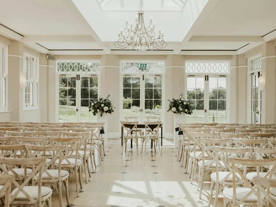 Elegant wedding event space with wooden chairs and floral decor in Coastal Env Centre.
