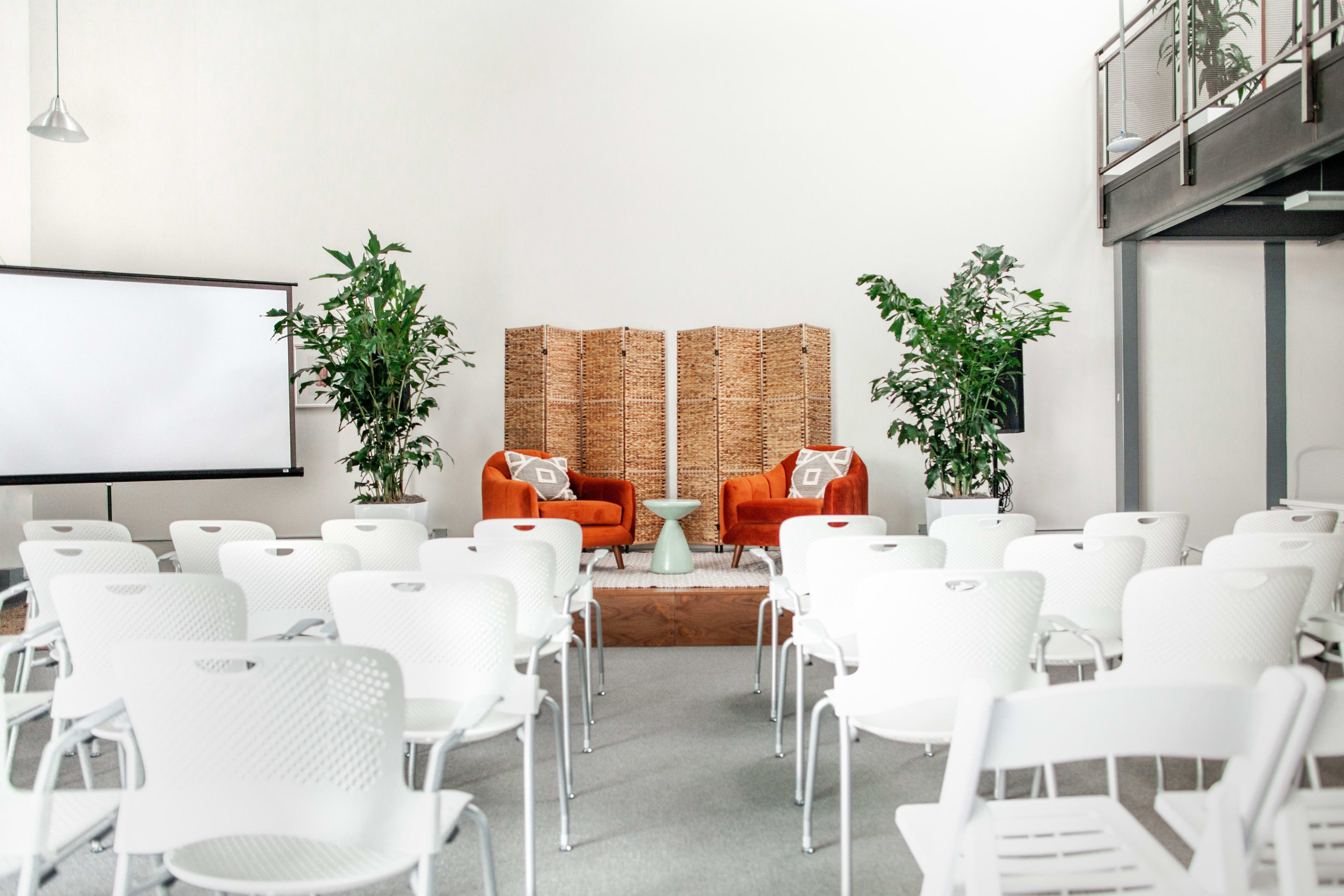 Main Room at Coastal Env Centre with orange chairs, perfect for presentations or gatherings.