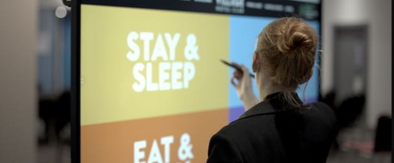 Engaged attendee at Village Hotel Reading's Inspiration Suite conference, vibrant digital screens.