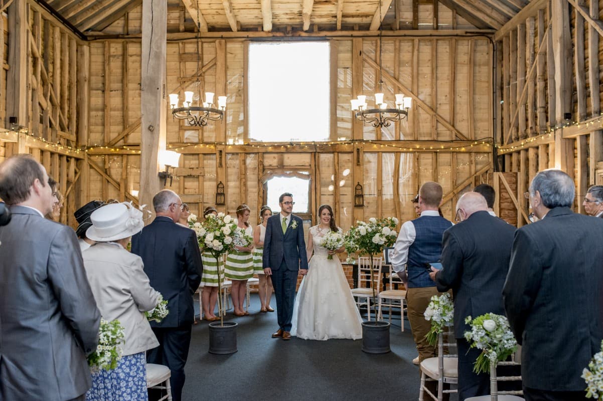 Rustic-chic wedding ceremony in Childerley Hall with timber frames and floral aisle decor.