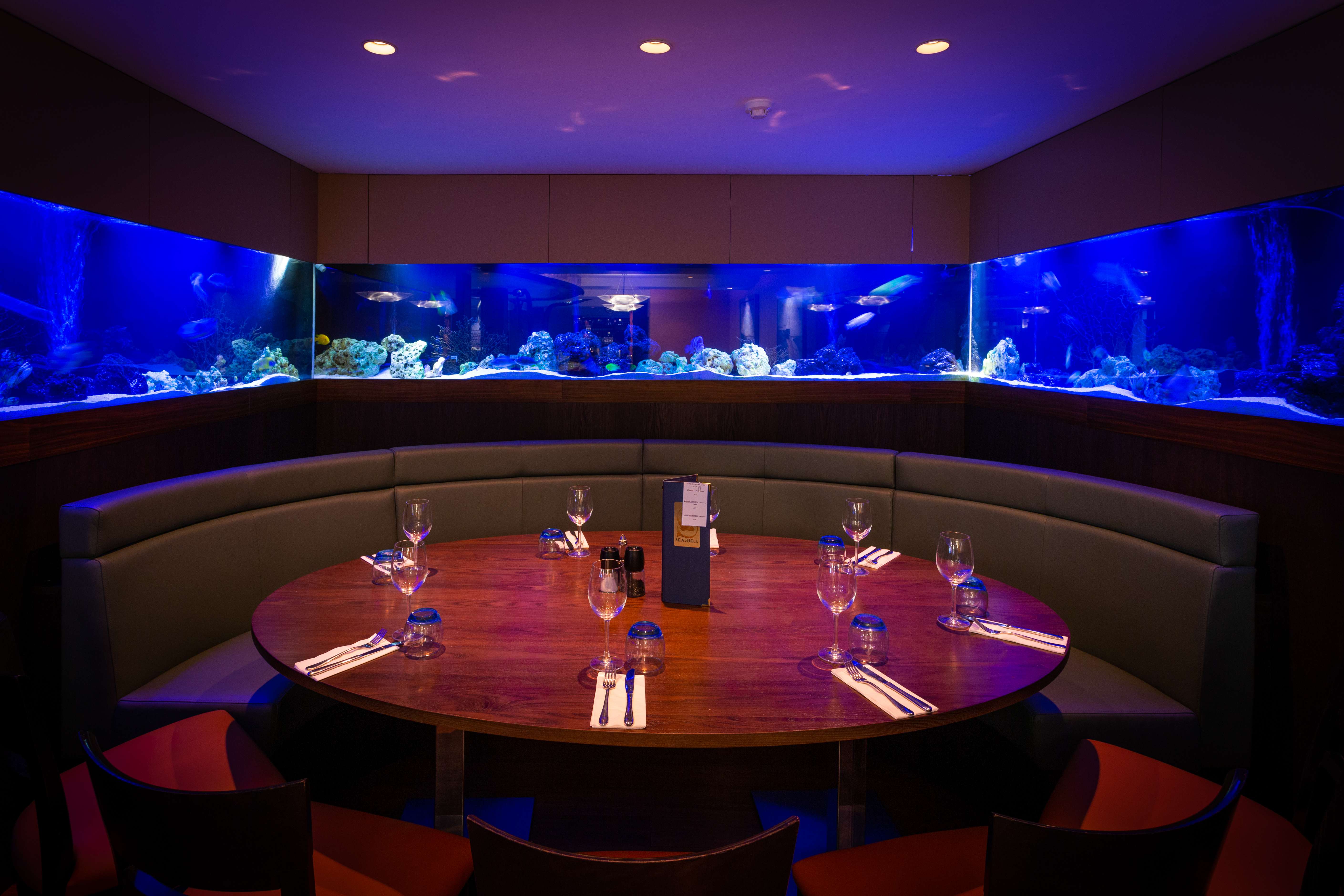 Private dining alcove with aquarium walls for VIP corporate events and intimate dinners.