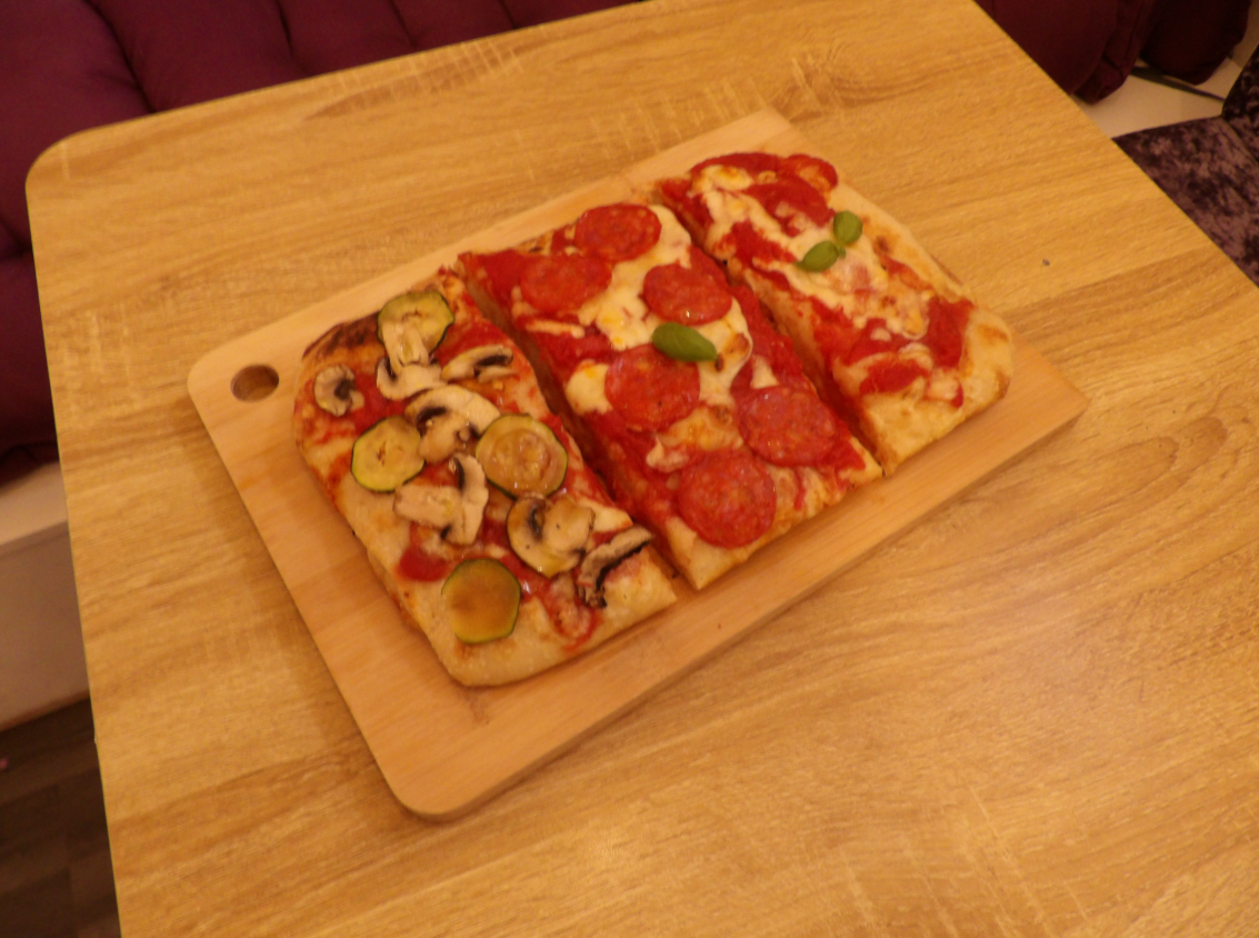Wooden serving board of assorted pizzas for casual gatherings and networking events.