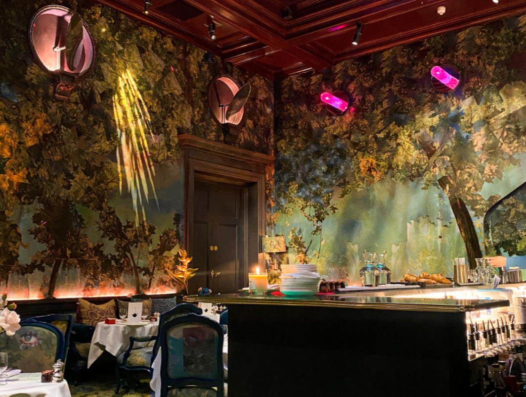 Elegant dining space with forest mural, ideal for upscale events and gatherings.