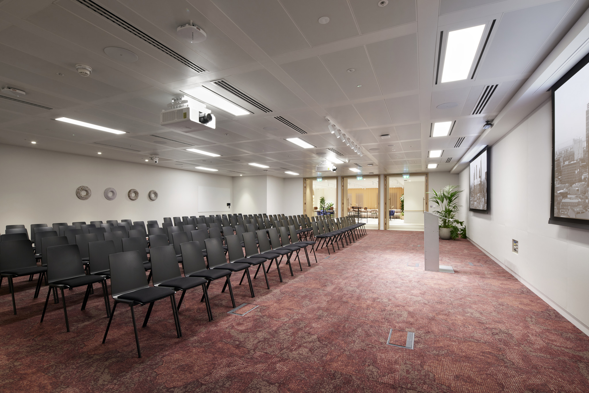 Conference room at Bon Hub with black chairs and projection screen for seminars.