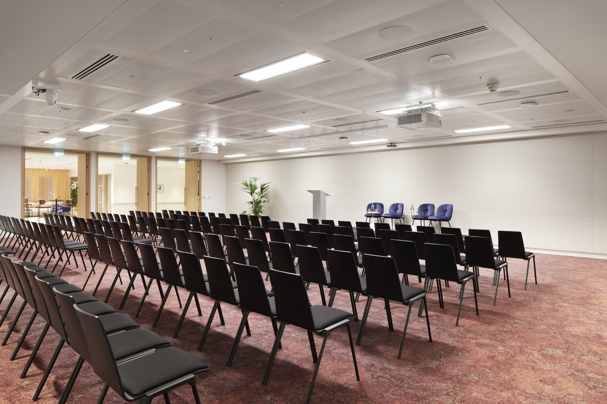 Conference room at Bon Hub with black chairs and podium for engaging events.