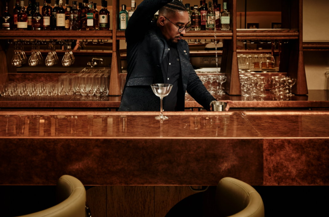 Skilled bartender crafting cocktails at Gambit Bar, upscale networking venue.