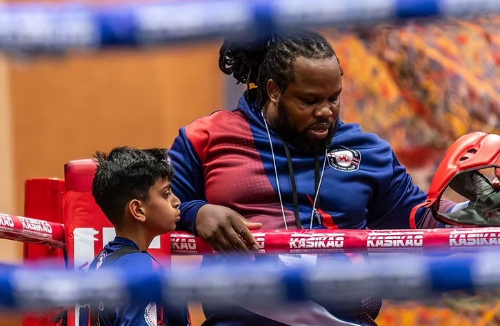 Focused coach mentoring young boxer in Martial Arts gym, highlighting sports mentorship.