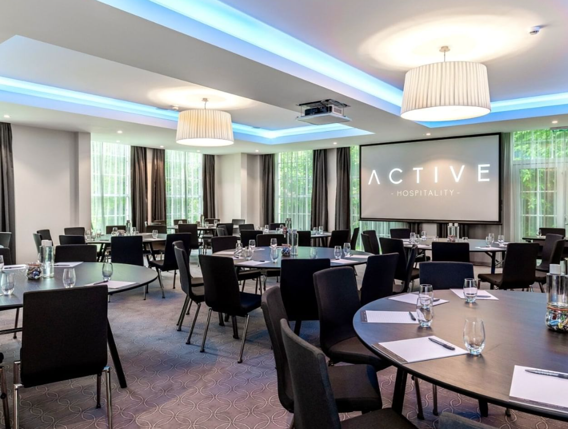Modern meeting room at Gorse Hill Hotel with round tables for corporate events.