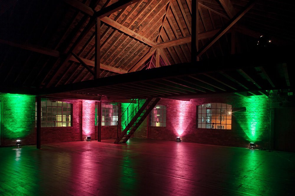 Versatile event space at 47/49 Tanner Street with exposed beams and dynamic lighting.