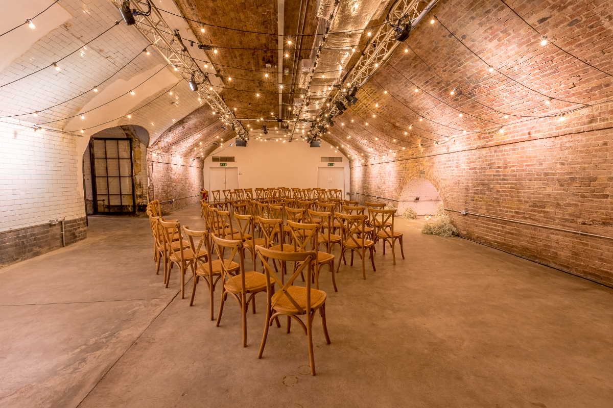 Versatile event space in Kachette with exposed brick and string lighting for gatherings.