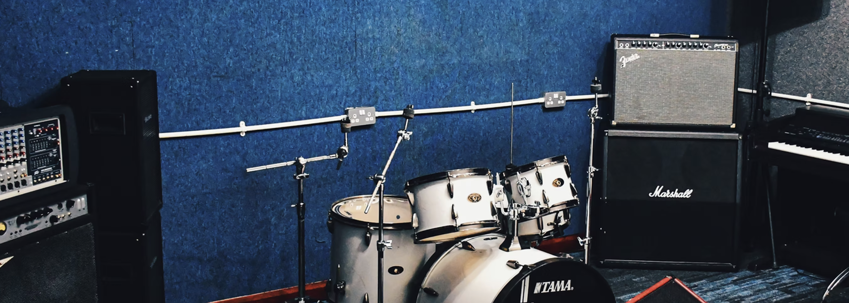 Live event studio with sleek drum kit and amplifier for music rehearsals and workshops.