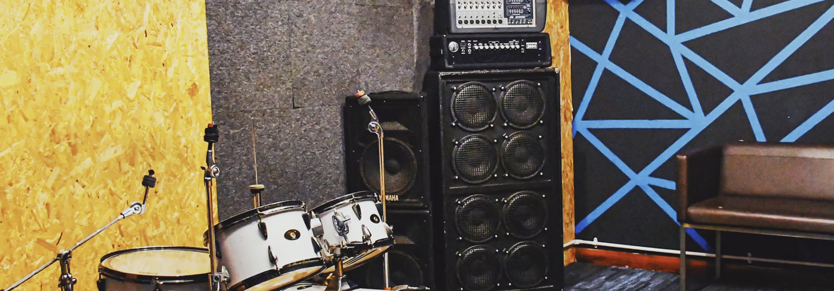 "Rehearsal studio with drum kit and amplifiers, ideal for live performances and music workshops."