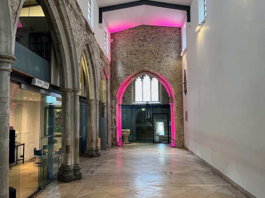 St Ethelburga's Centre nave with stone arches, vibrant lighting for events and gatherings.