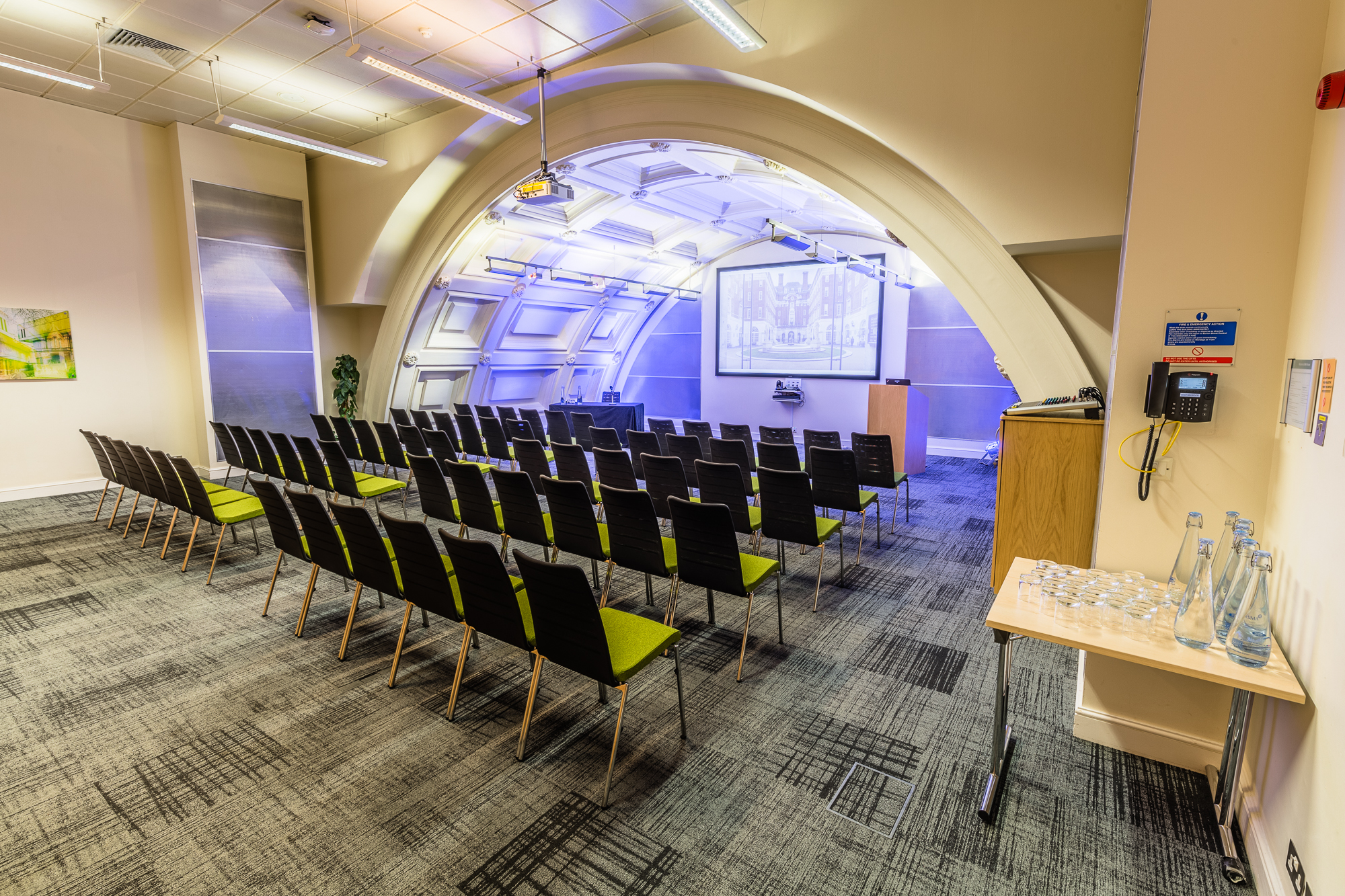 Modern event space with black chairs for conferences at BMA House, featuring a large screen.