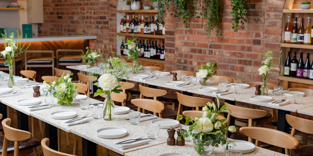 Elegant dining space for private events with floral centerpieces and warm brick walls.