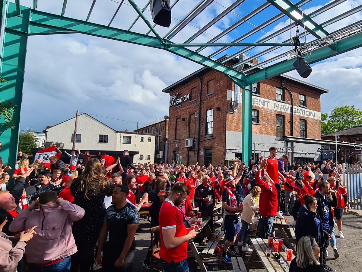 Outdoor event at The Big Shed, Ye Olde Trip to Jerusalem, with crowd in red attire.