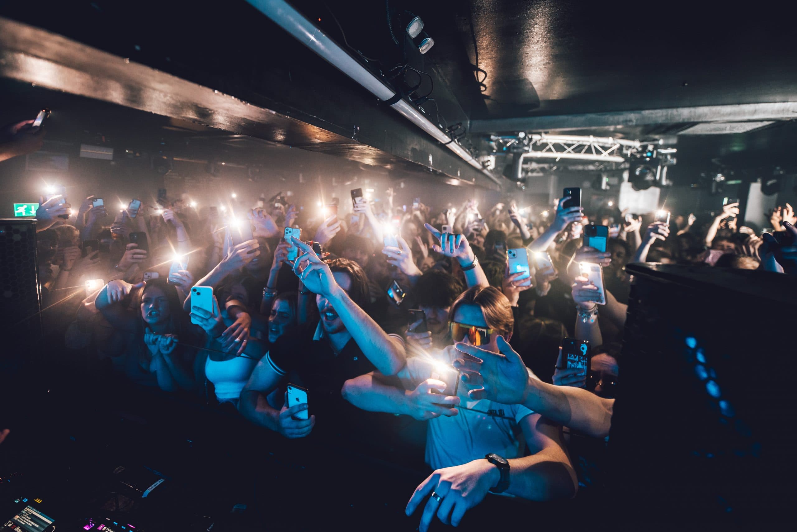 Vibrant crowd at a live event with phone screens, highlighting audience engagement and interaction.