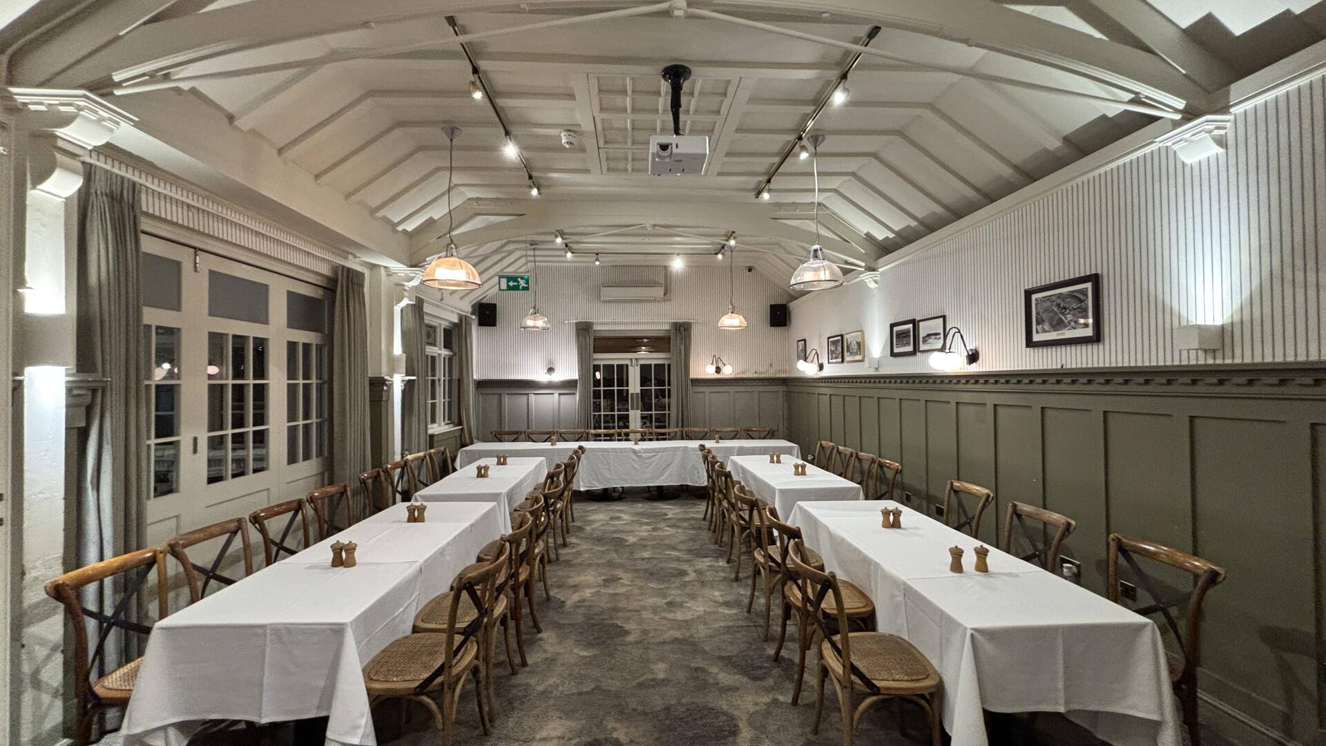Elegant boudoir event space with long tables, ideal for meetings and networking.
