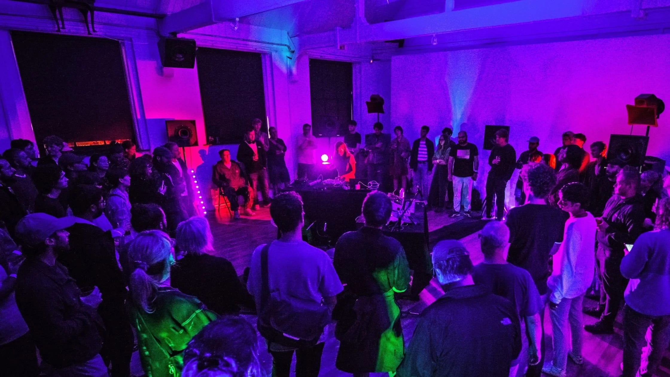 Vibrant IKLECTIK gig with engaged audience in colorful lighting for music events.