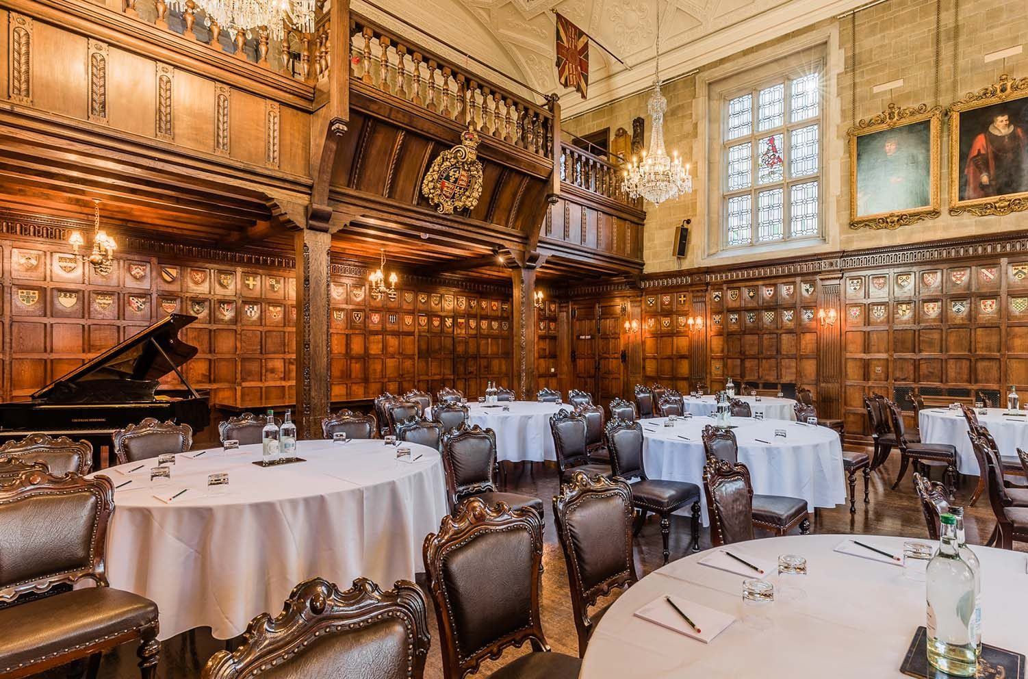 Elegant Banqueting Hall with round tables and grand piano, perfect for corporate events.
