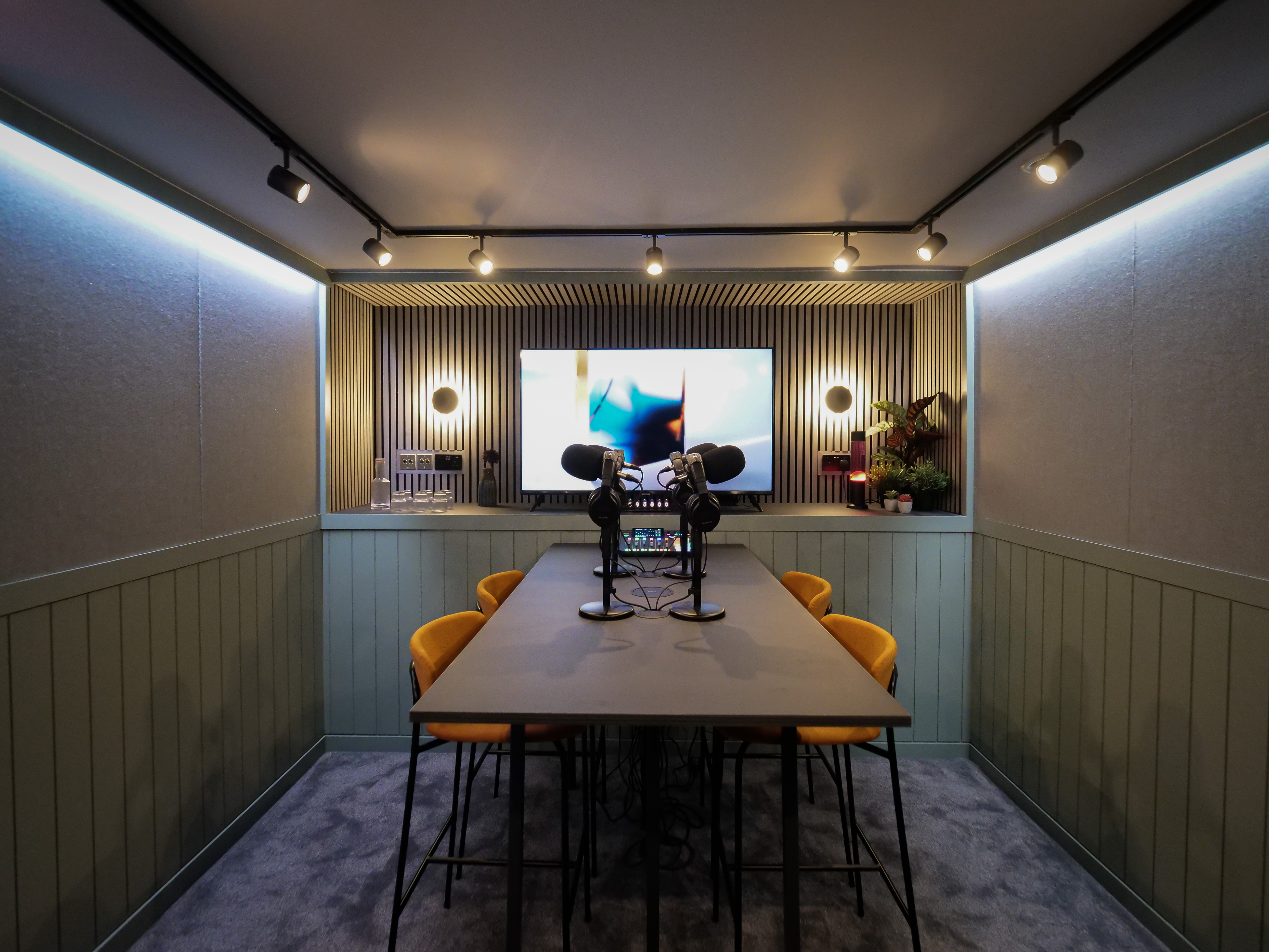 Podcast room with sleek table, mics, and bright orange chairs for creative meetings.
