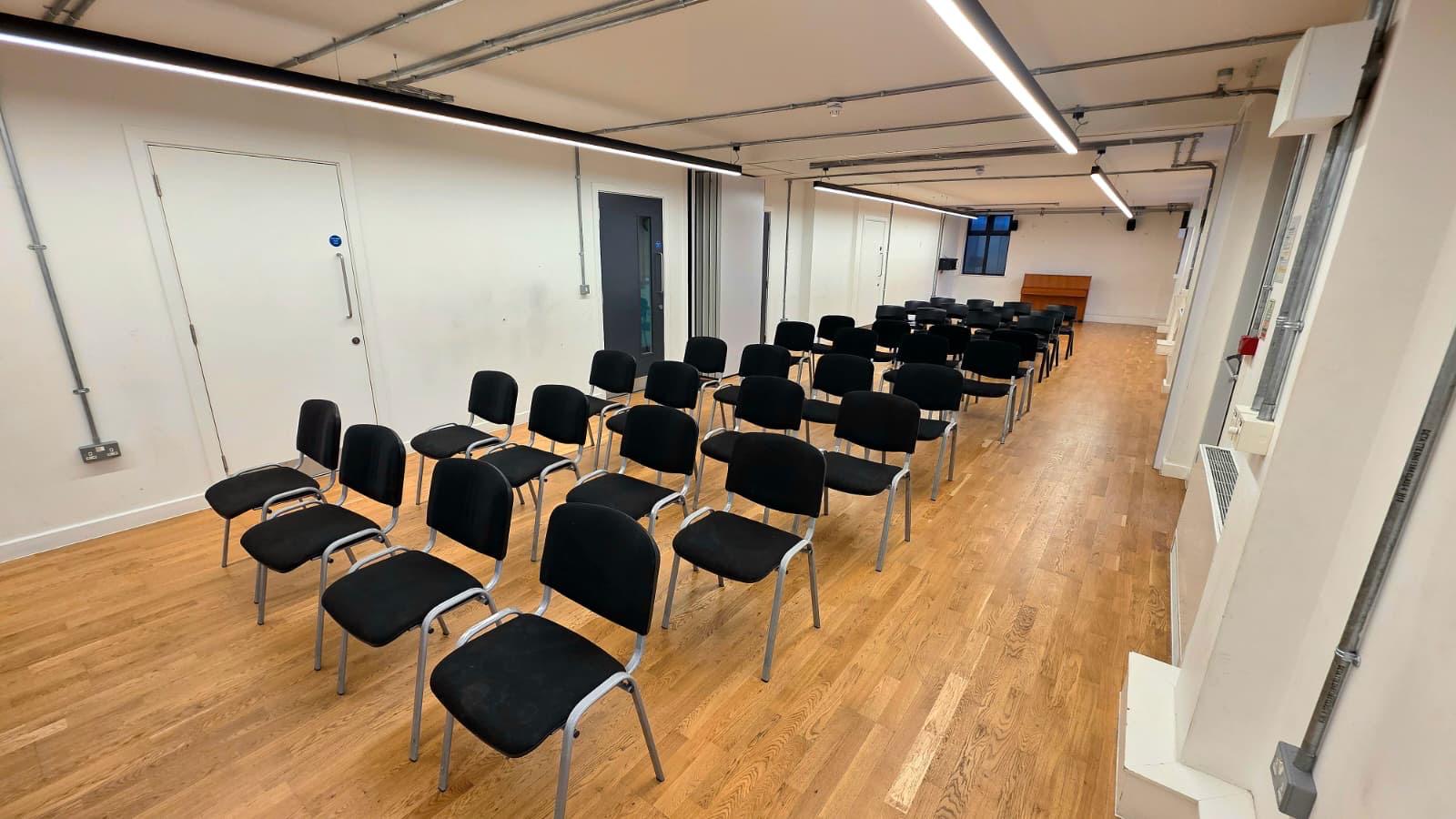 Alt tag: "Studio 3 Chelsea Theatre meeting space with black chairs for workshops or presentations."