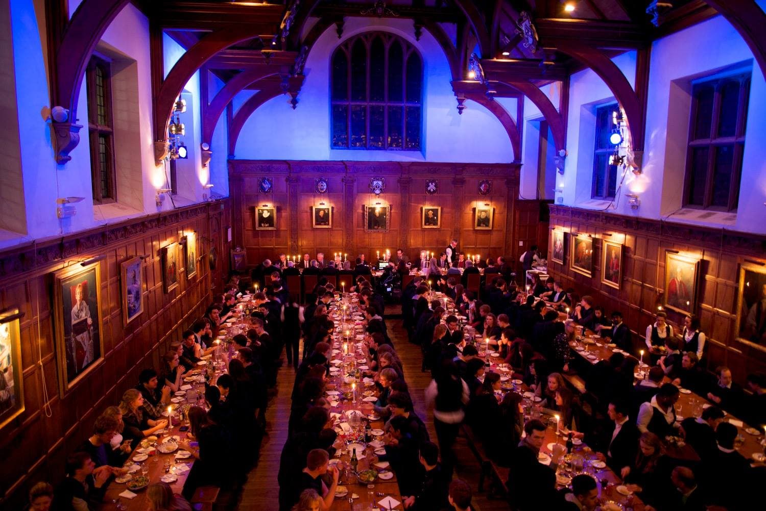 Gala dinner in historic Gonville and Caius College hall with elegant blue uplighting.