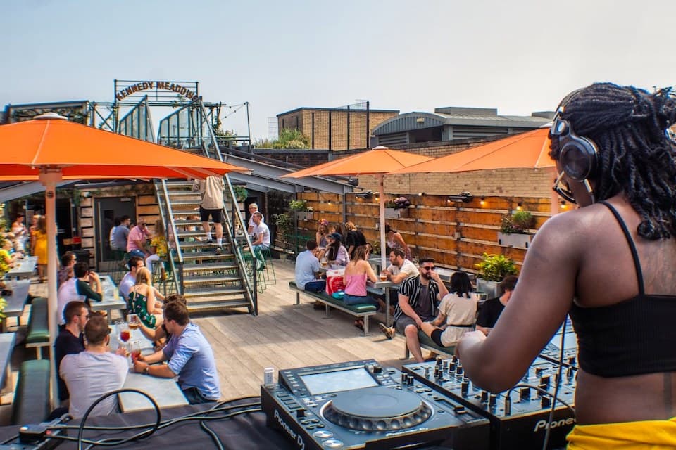 Rooftop beer garden event, outdoor seating, DJ booth.