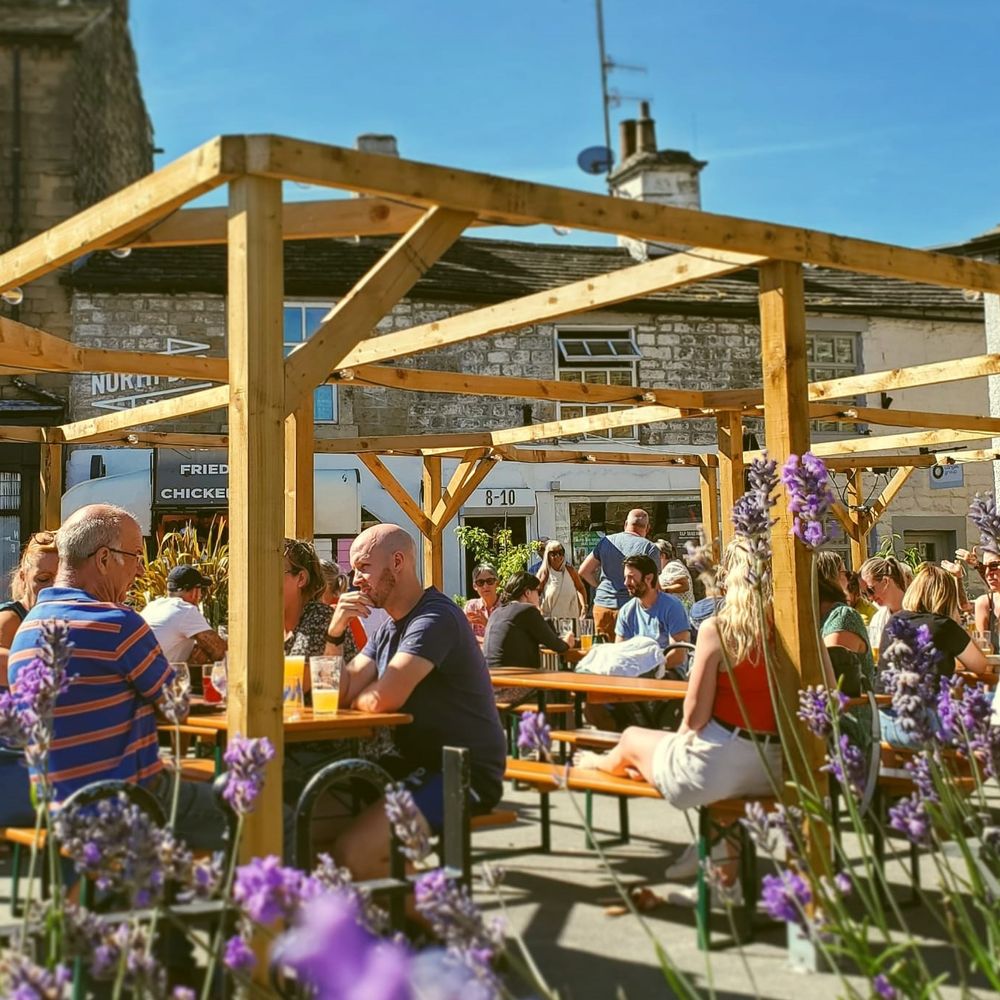 Outdoor beer garden event, rustic pergola, casual venue.