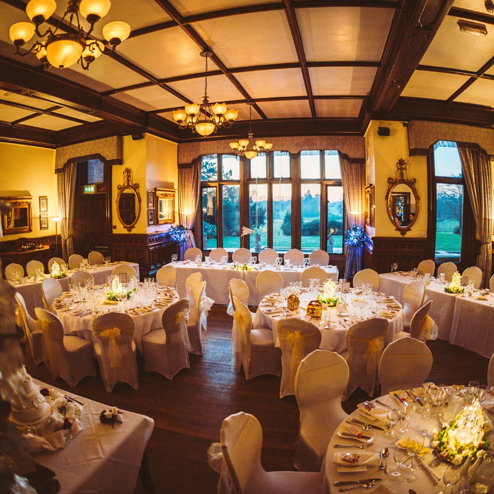 Elegant banquet room with white tables and gold accents, perfect for weddings or galas.