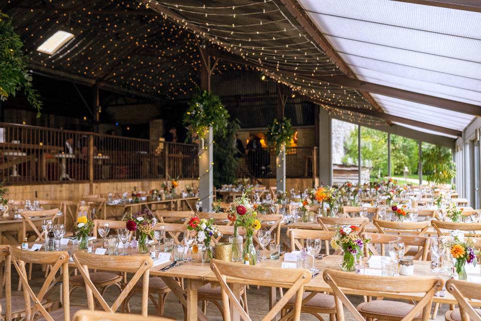 Rustic barn wedding venue with communal tables for upscale banquet events.