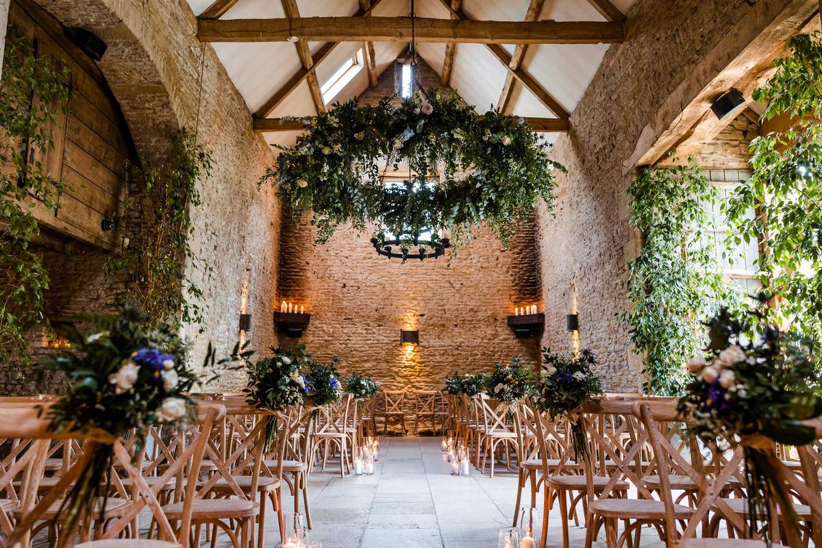 Rustic Stone Barn wedding ceremony with floral chandelier decor.