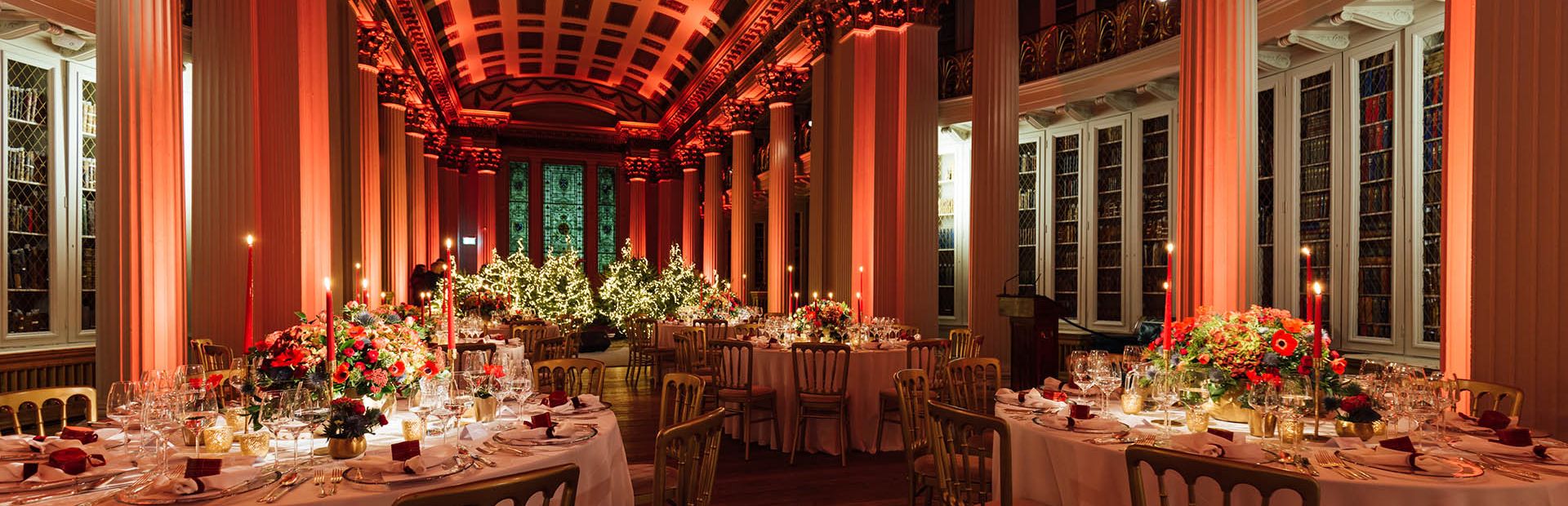 Gala dinner at Signet Library with dramatic red lighting for luxury events and historic venue hire.