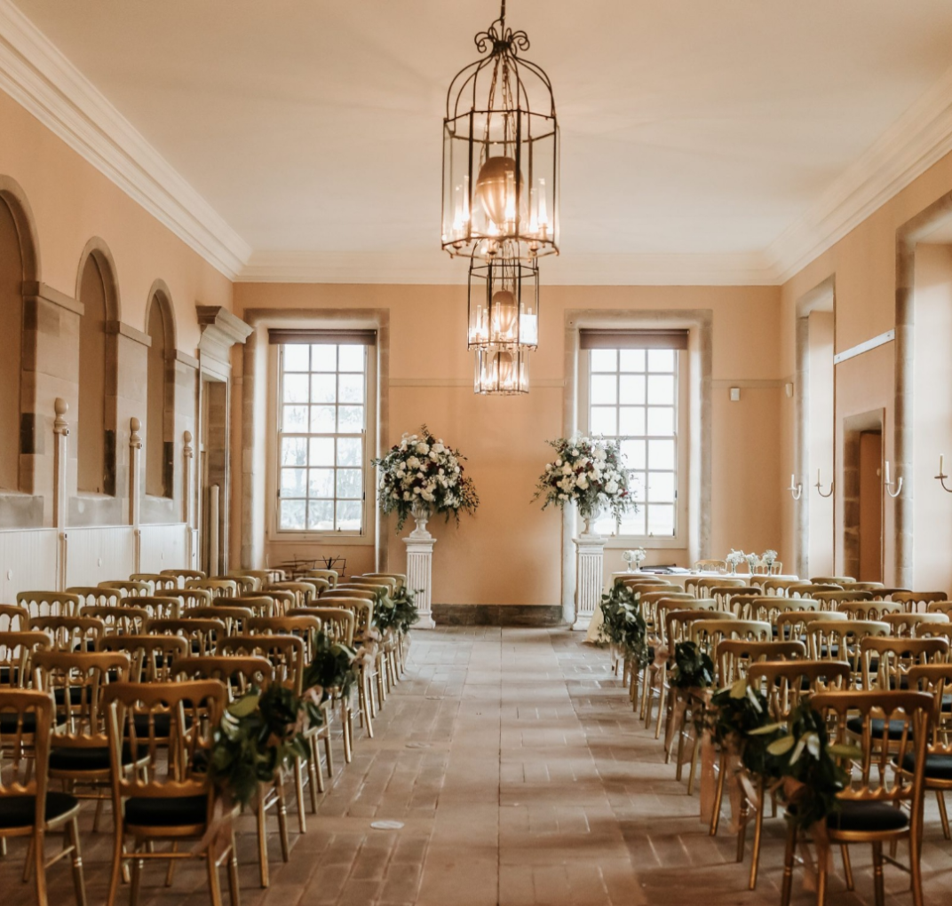 Elegant wedding ceremony with gold chairs and floral decor at a historic venue.