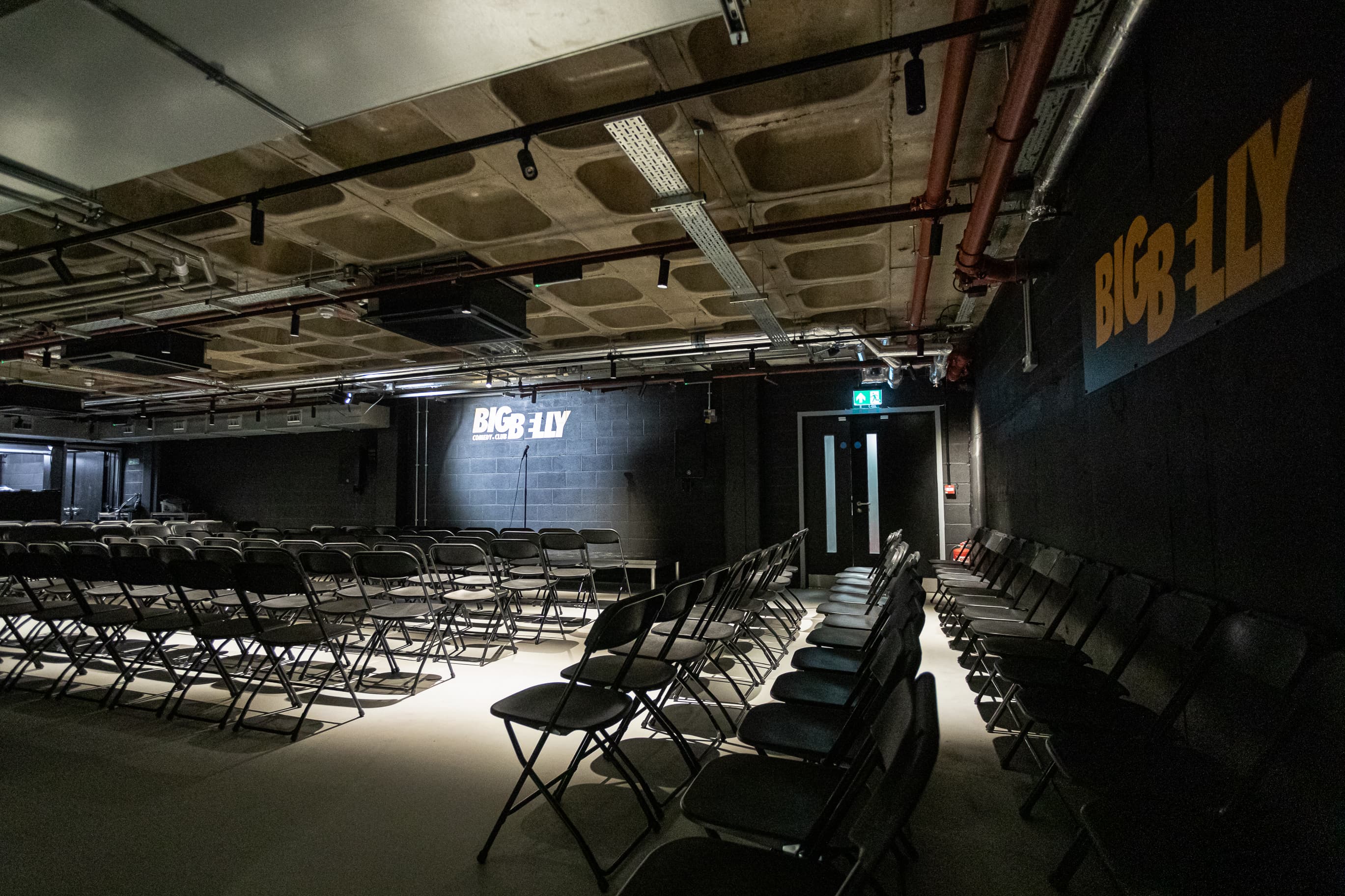 Big Belly Room industrial black-box venue set for comedy shows and corporate presentations.
