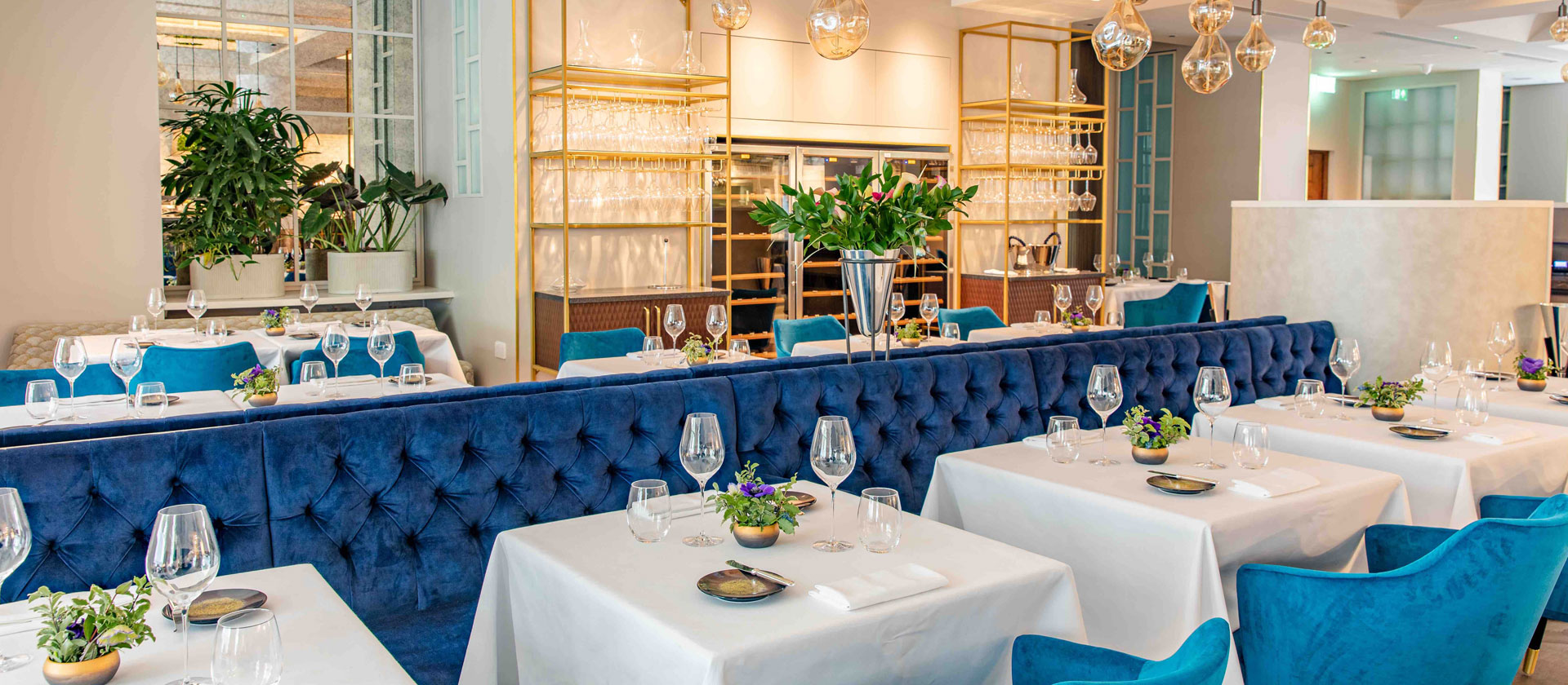 Elegant Cord Café with blue tufted banquettes for corporate luncheons and gala dinners.