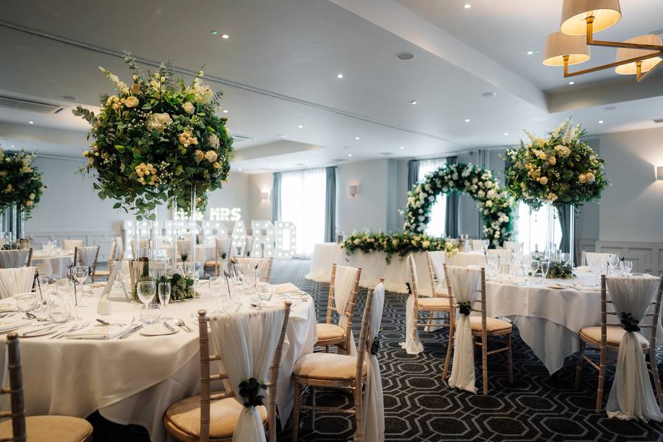 Sophisticated wedding ballroom reception at De Vere Cranage Estate with elegant floral centerpieces.