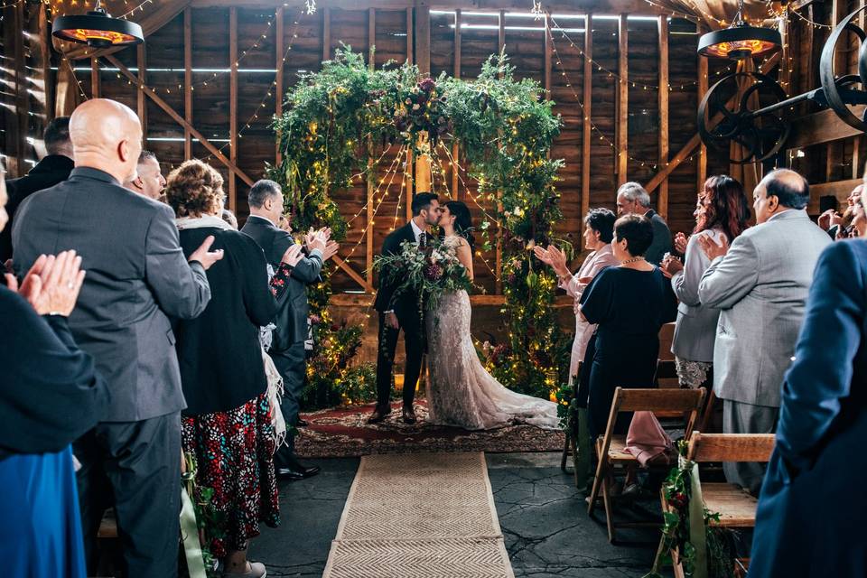 Rustic-chic wedding ceremony with floral arch at The Granary barn venue.