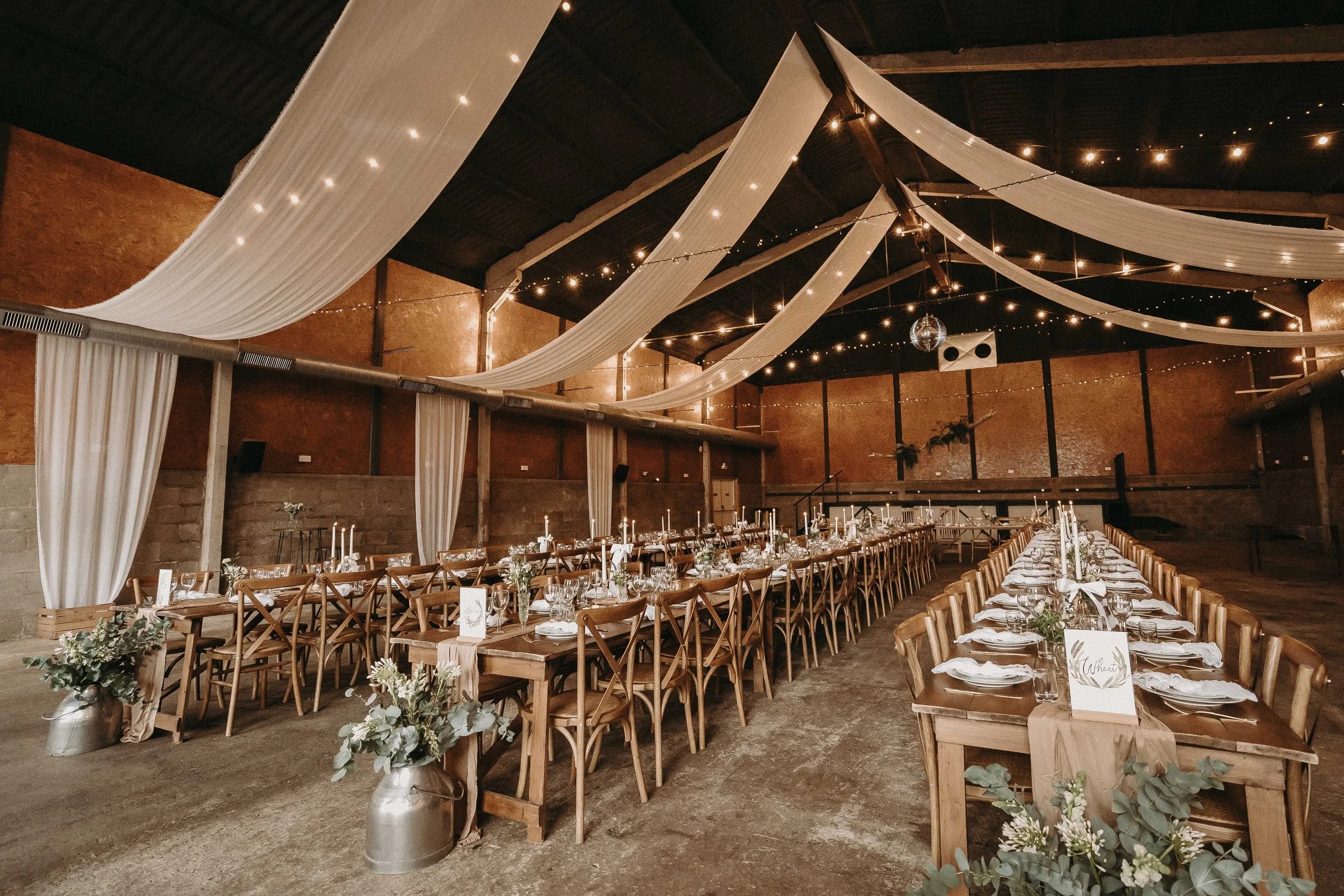 Rustic-chic barn wedding venue at The Boulton & Paul Bar with elegant drapery and string lighting.