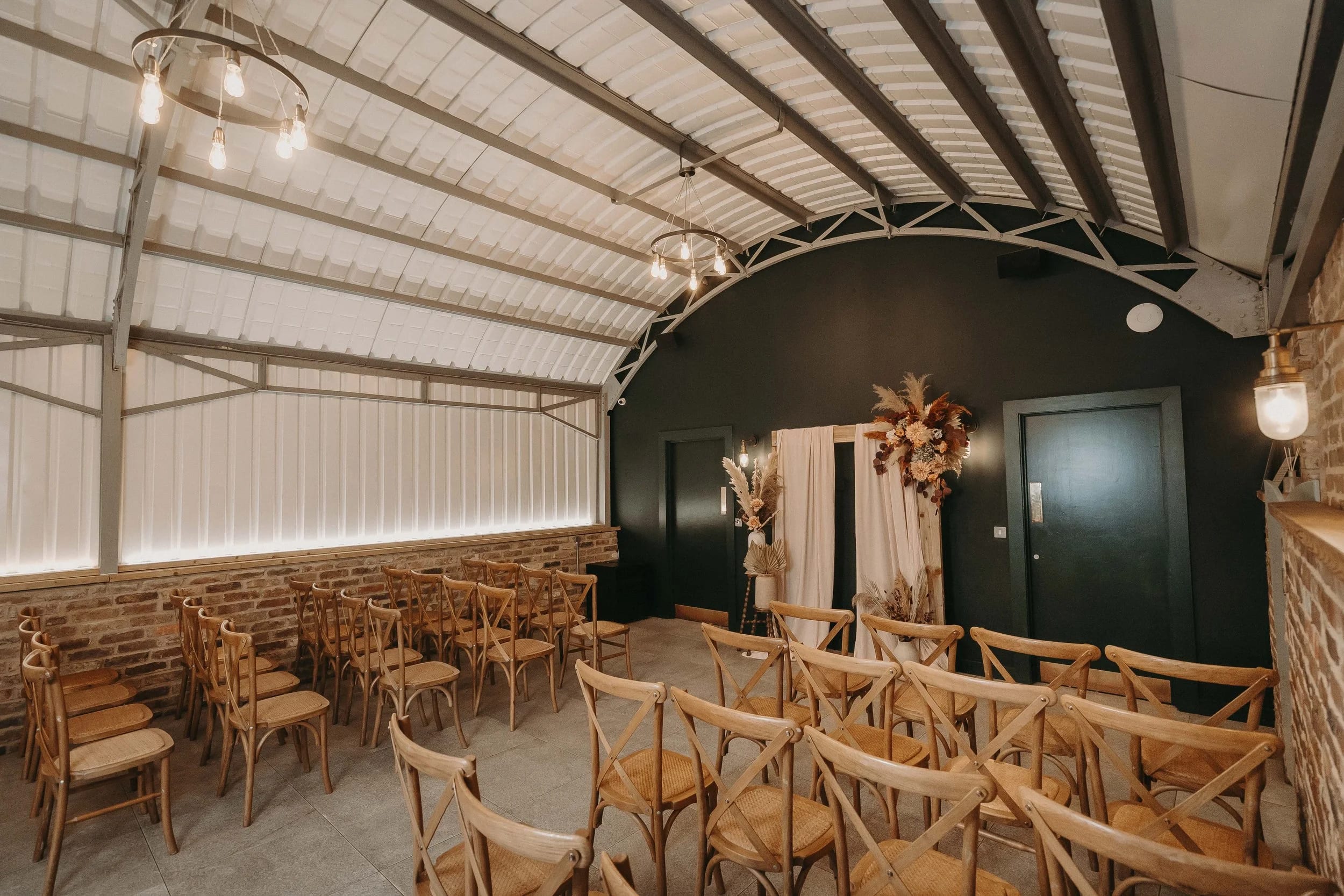 Industrial-chic wedding ceremony at The Old Workshop, Lodge Farm with cross-back chairs.